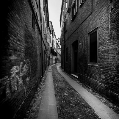 Black White Aufnahme einr Gasse mit Backsteingebäuden daneben.