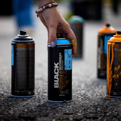 Spraydosen stehen am Boden und jemand greift danach