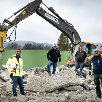 4 Männer stehen vor großem Baugerät auf Baustelle und schauen in die Kamera