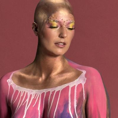 Kreatives Bodypainting mit goldener Haut und farbigen Akzenten im Gesicht, künstlerisches Portrait im Studio