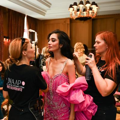 Make-up Artists stylen Model im pinken Kleid backstage bei Fashion Show