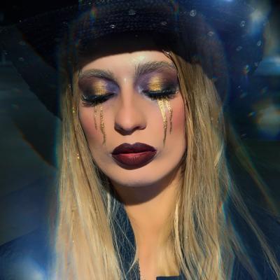 Frau mit dunklem Glamour-Make-up und Hut im künstlerischen Lichtsetting
