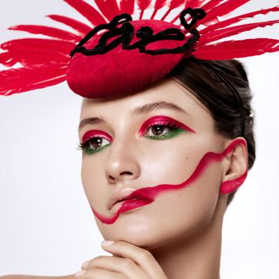 Porträt einer Frau mit künstlerischem Make-up und rotem Kopfschmuck im Studio
