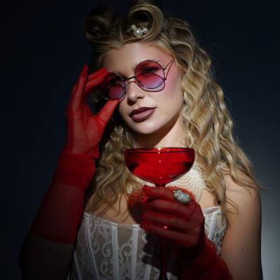 Frau im Retro-Styling mit rotem Glas und Sonnenbrille im dunklen Lichtsetting