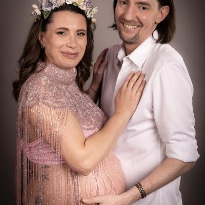 Schwangere Frau mit Babybauch und Partner bei emotionalem Paarshooting im Studio
